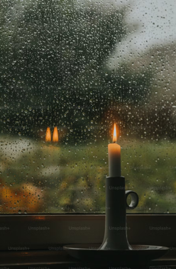 Regen an der Scheibe und Kerze auf dem Tisch.