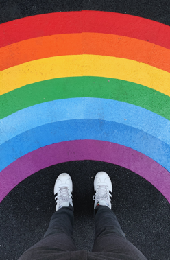 Mann, der vor einem Regenbogen steht